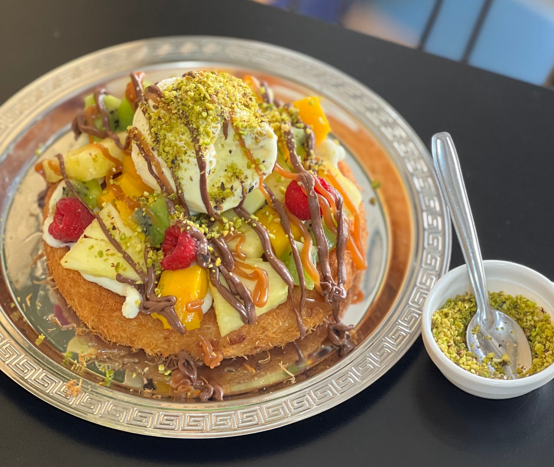 Gros plan sur la préparation d'un kunafa doré et croustillant, avec du fromage fondant et un sirop sirupeux.